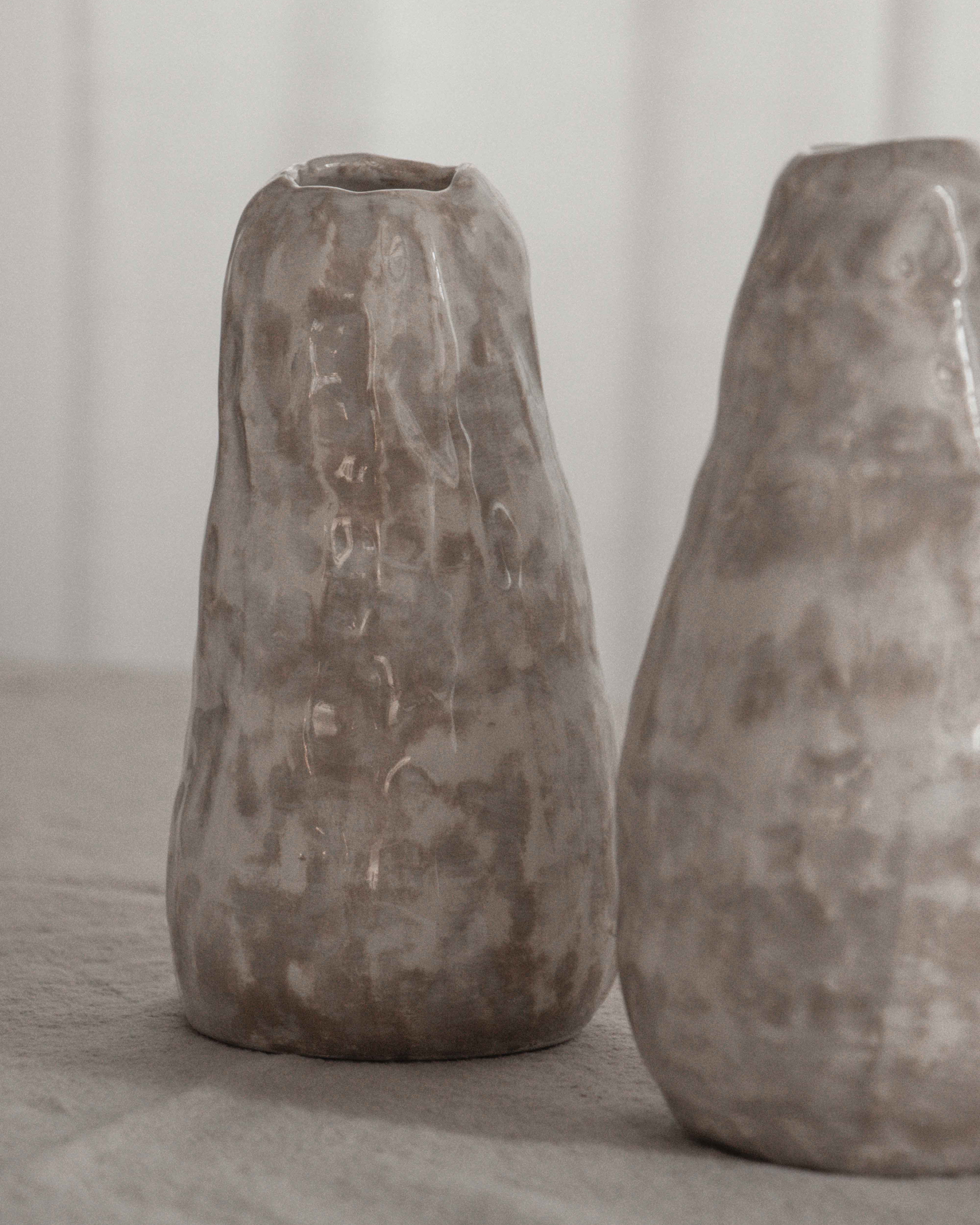 Two rustic stone vases on a neutral background