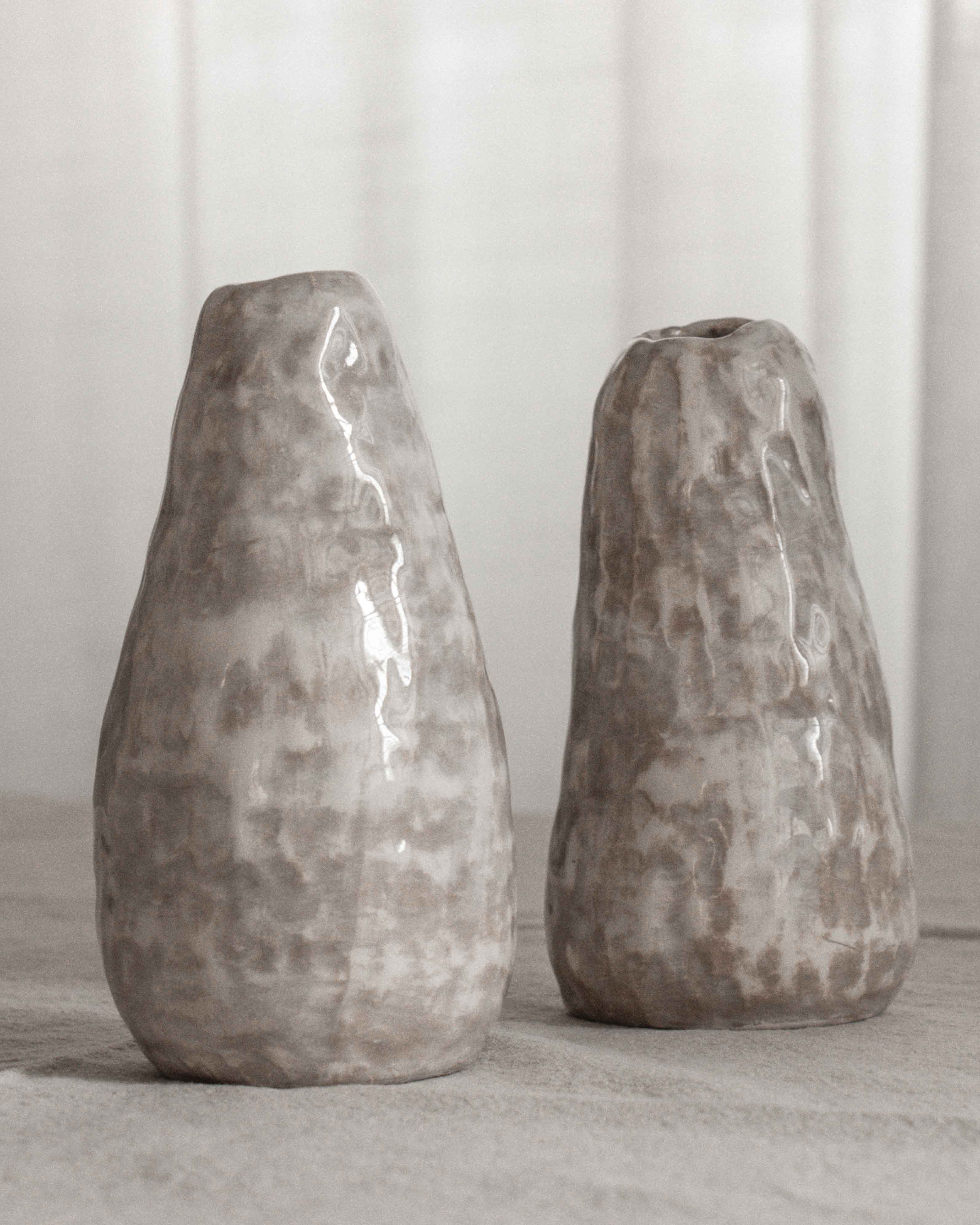Two textured ceramic vases on a light surface with a neutral background