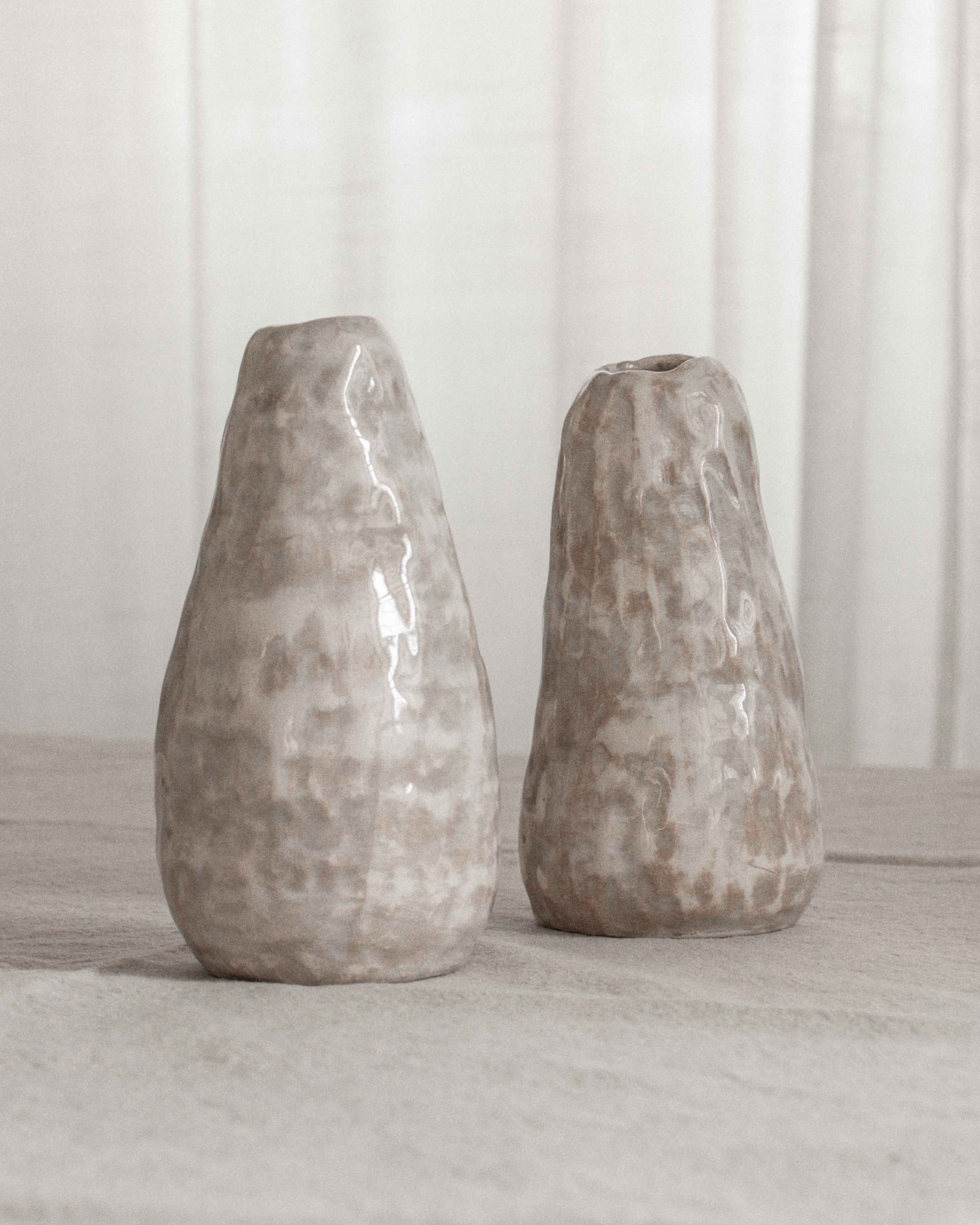 Two textured vases on a light surface with a neutral background
