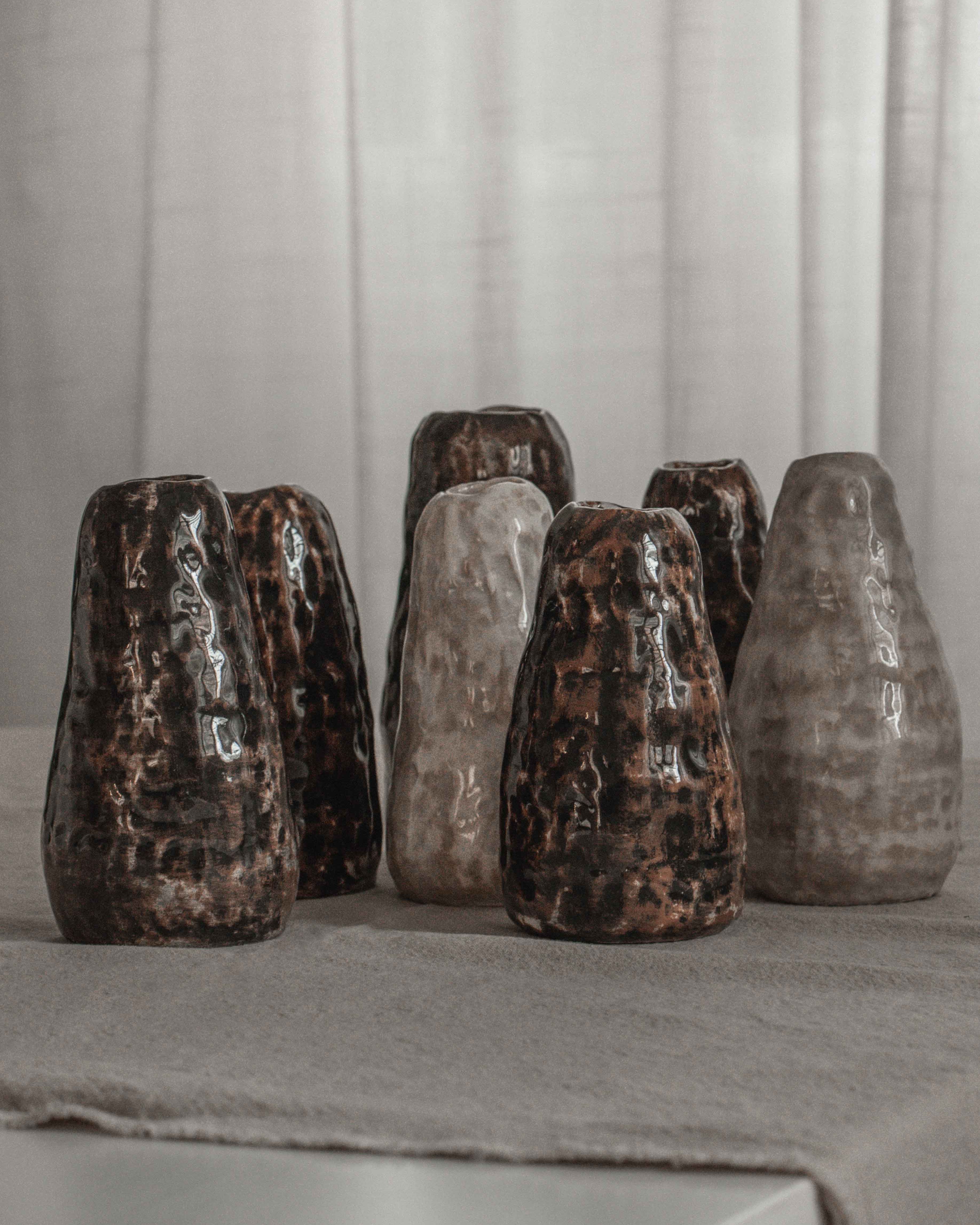 Set of six ceramic vases with a textured finish on a gray surface.