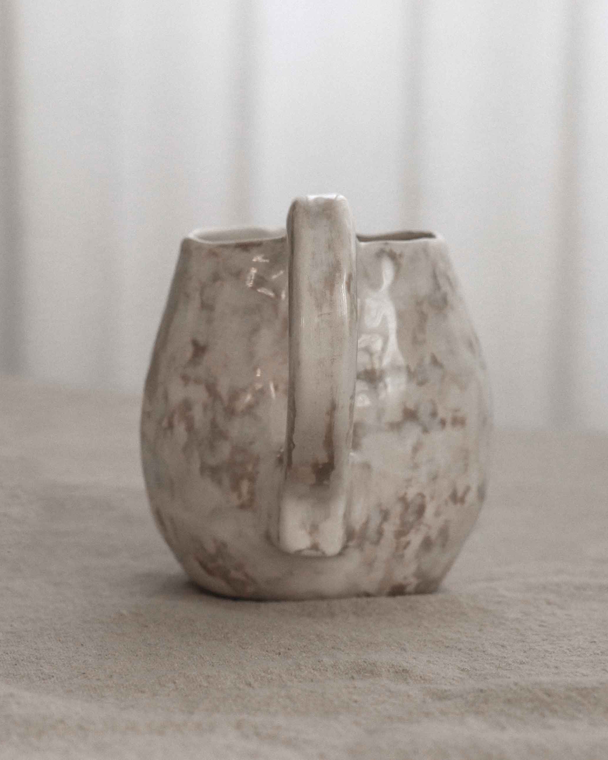 Ceramic vase with a handle on a neutral background