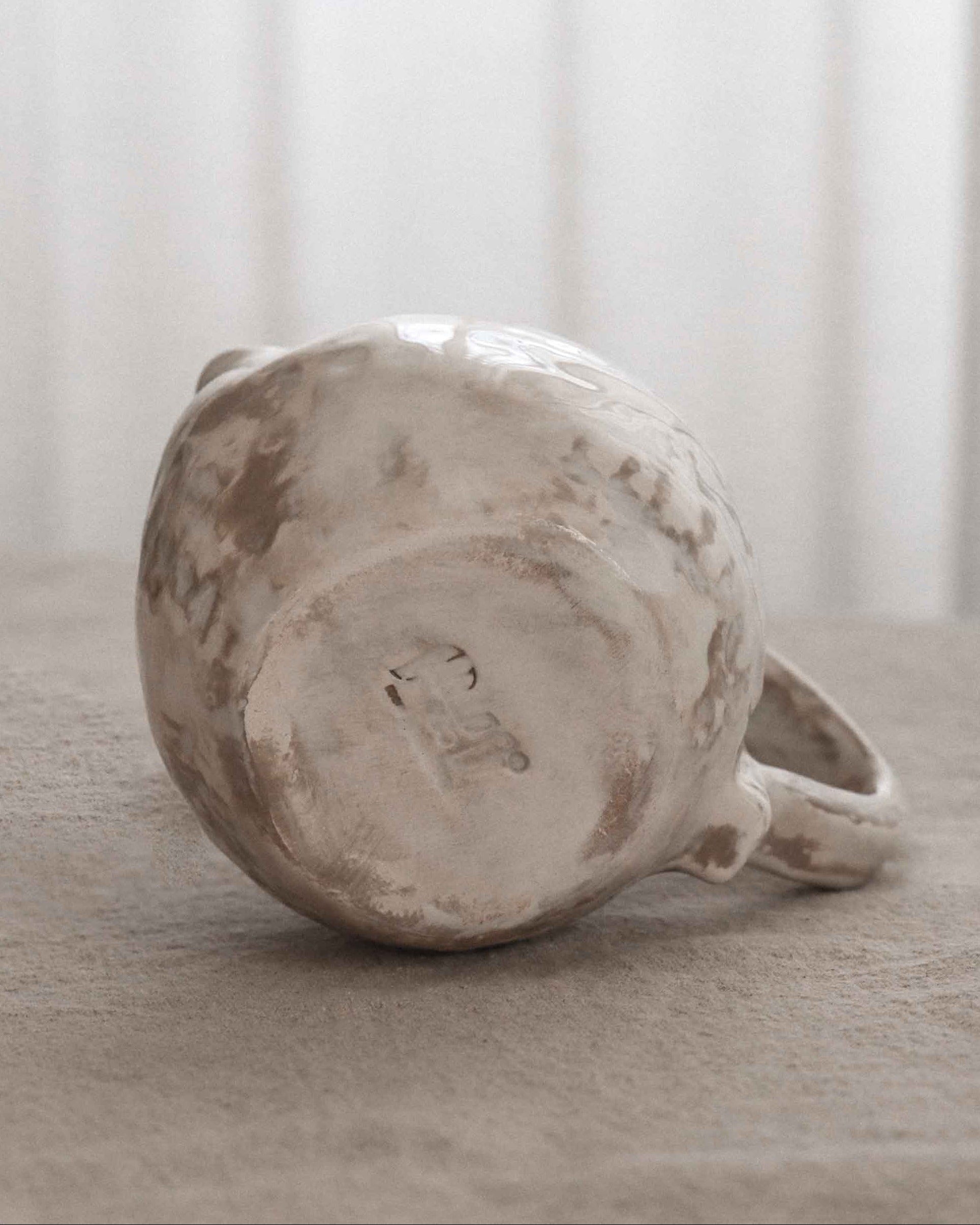 Milk pitcher piece on a neutral surface with a blurred white curtain background