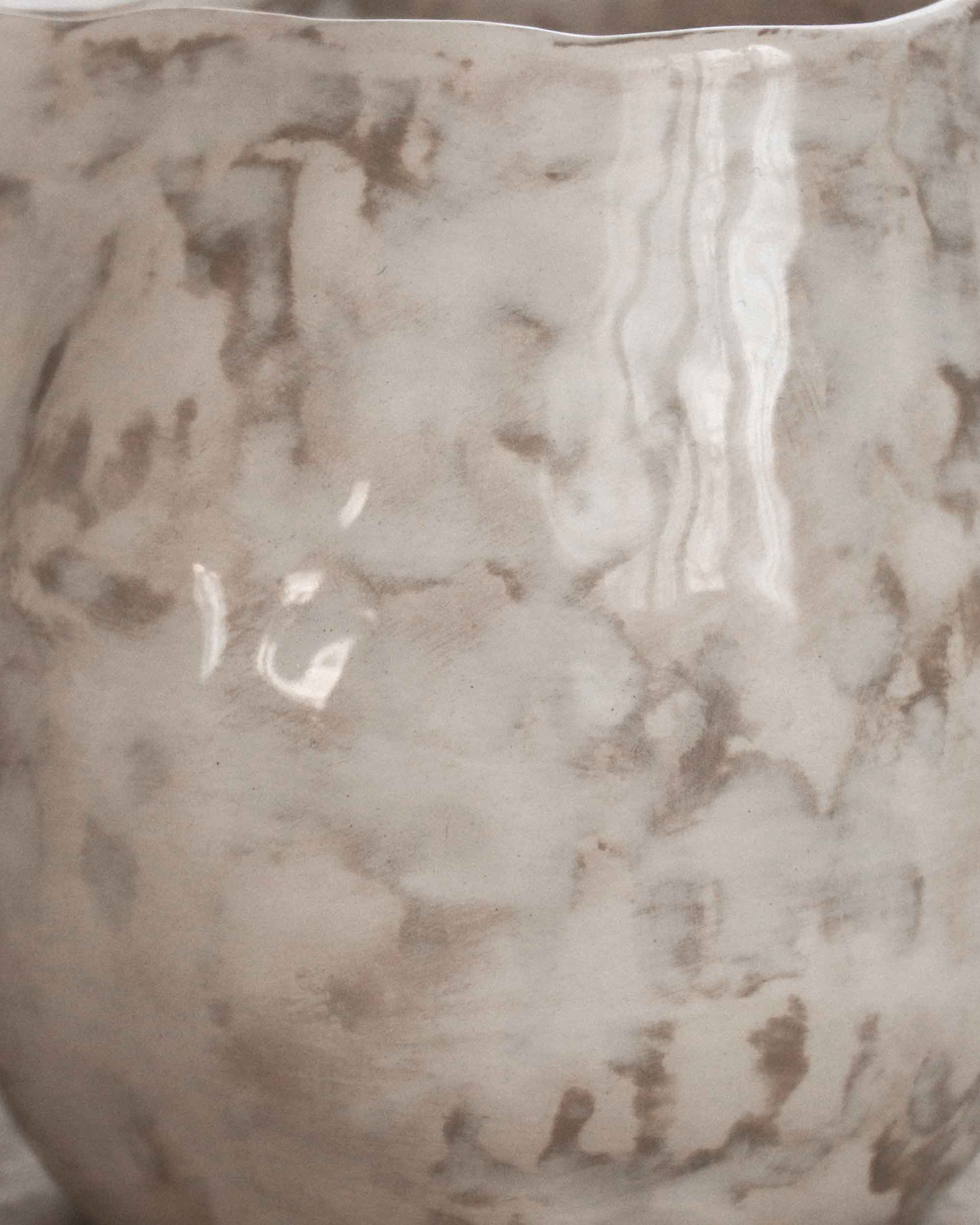 Decorative ceramic pitcher with a textured surface on a neutral background