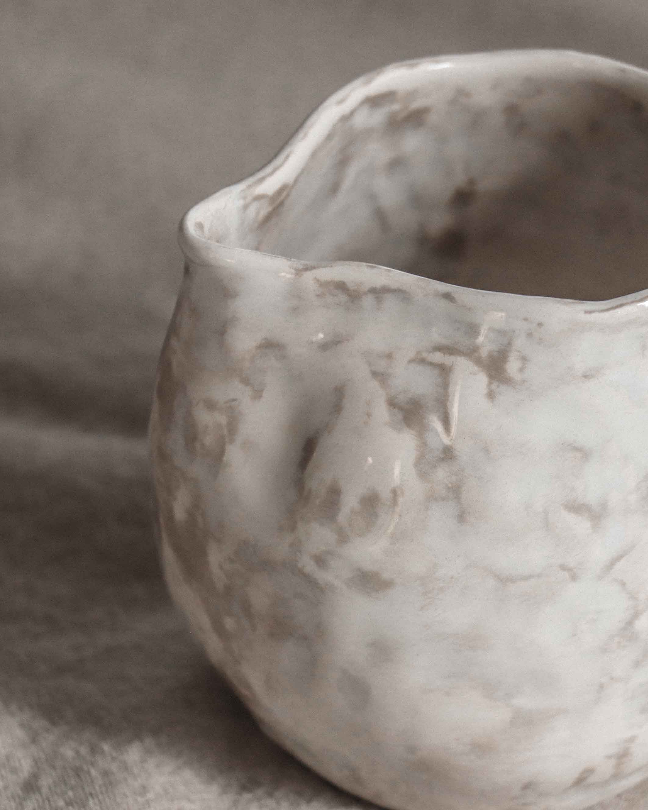 White ceramic pitcher with a handle on a gray background