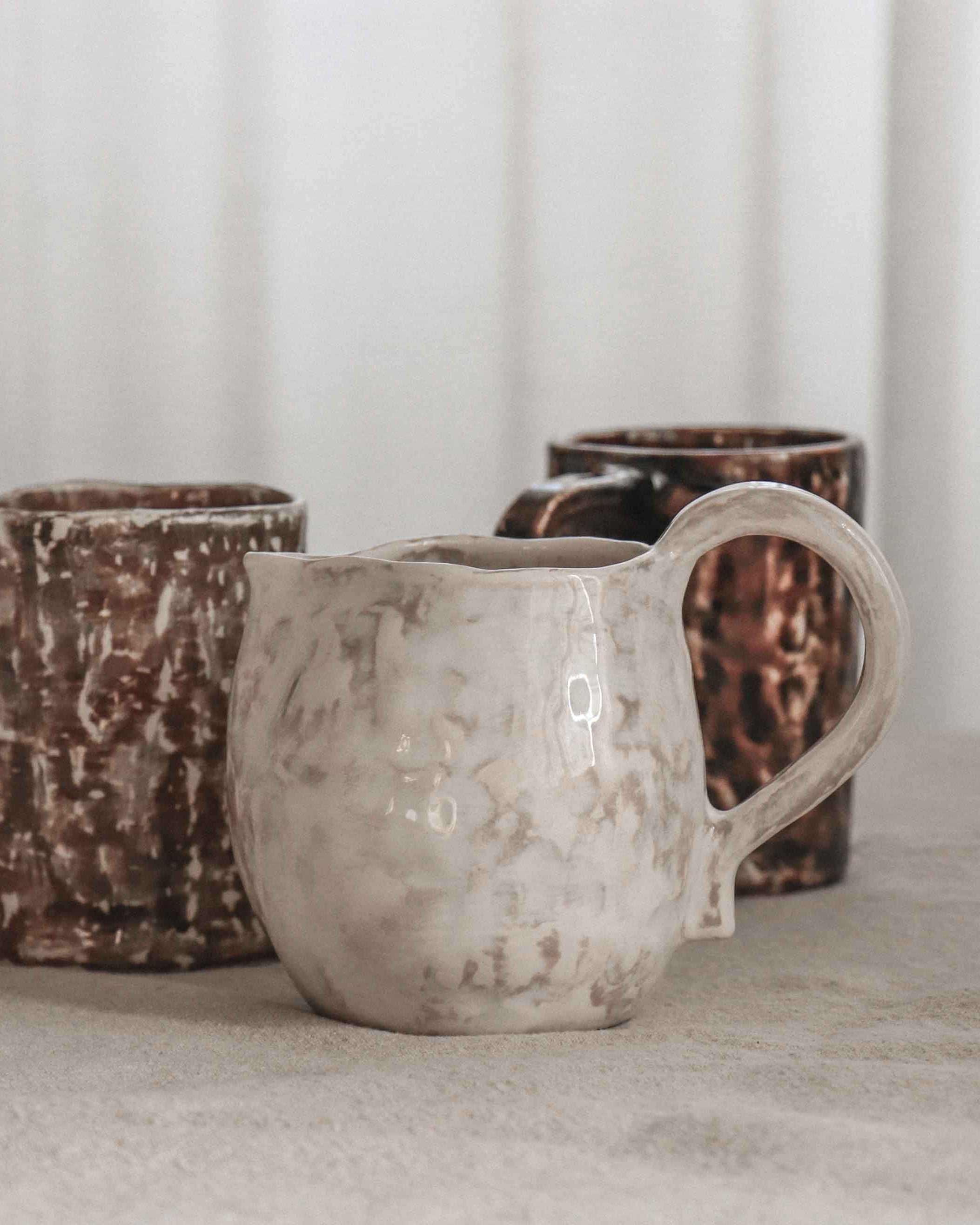 Three ceramic mugs with textured surfaces on a neutral background