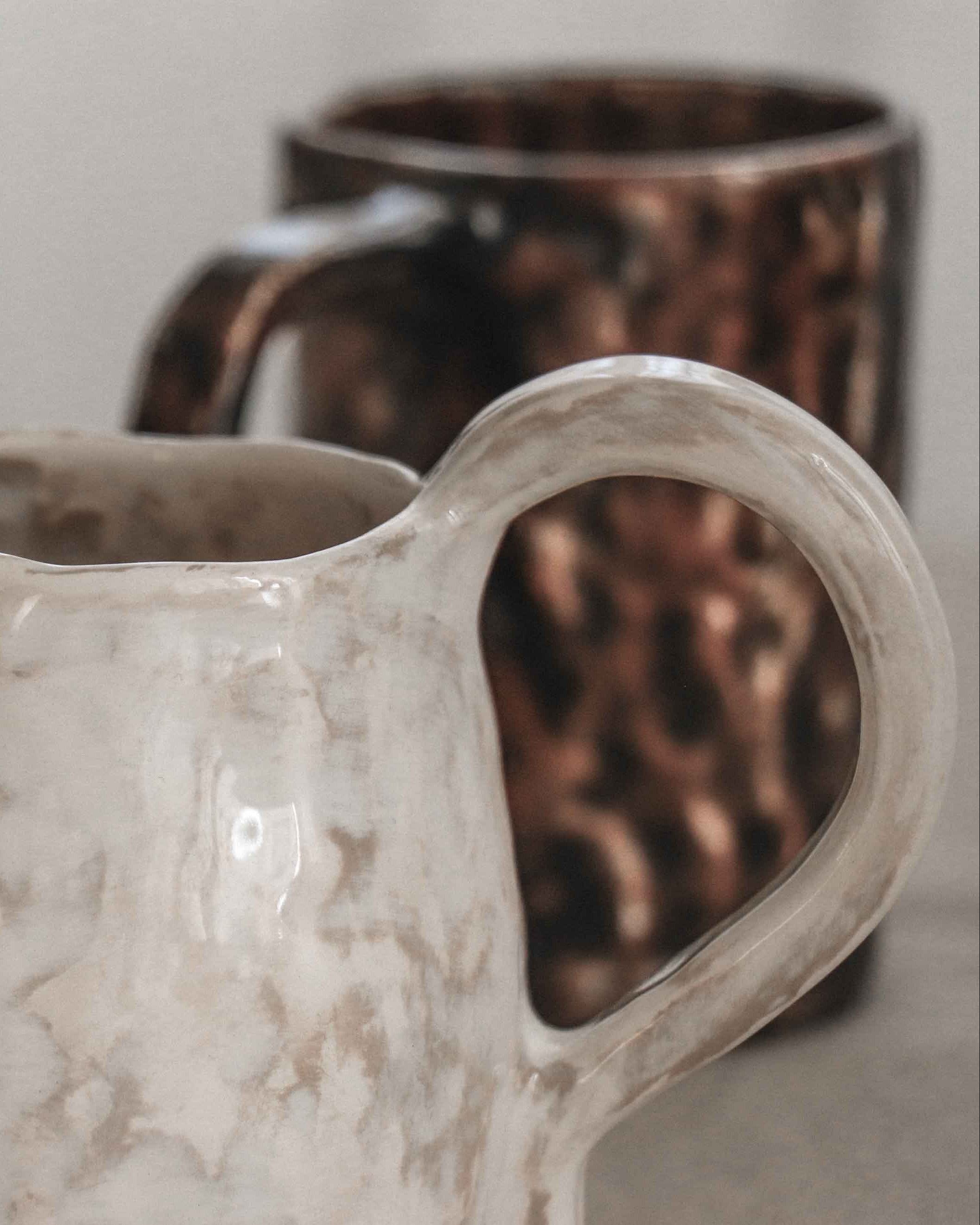 Two ceramic vessels with different designs on a neutral background