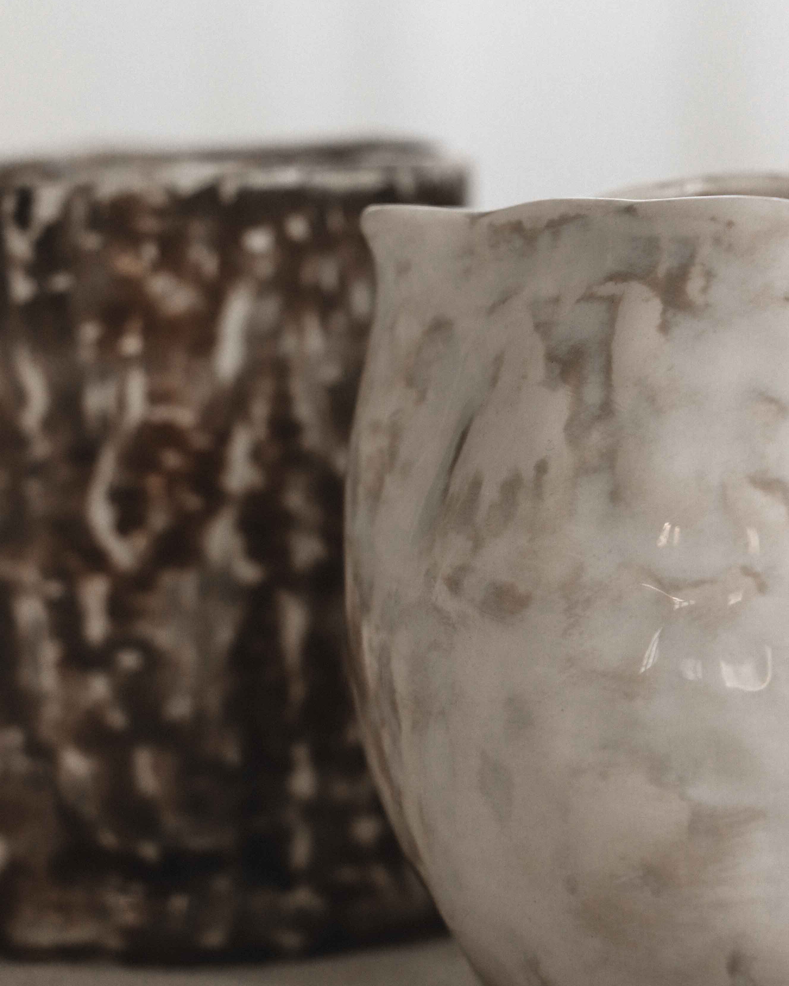 Two ceramic pots with textured surfaces on a neutral background