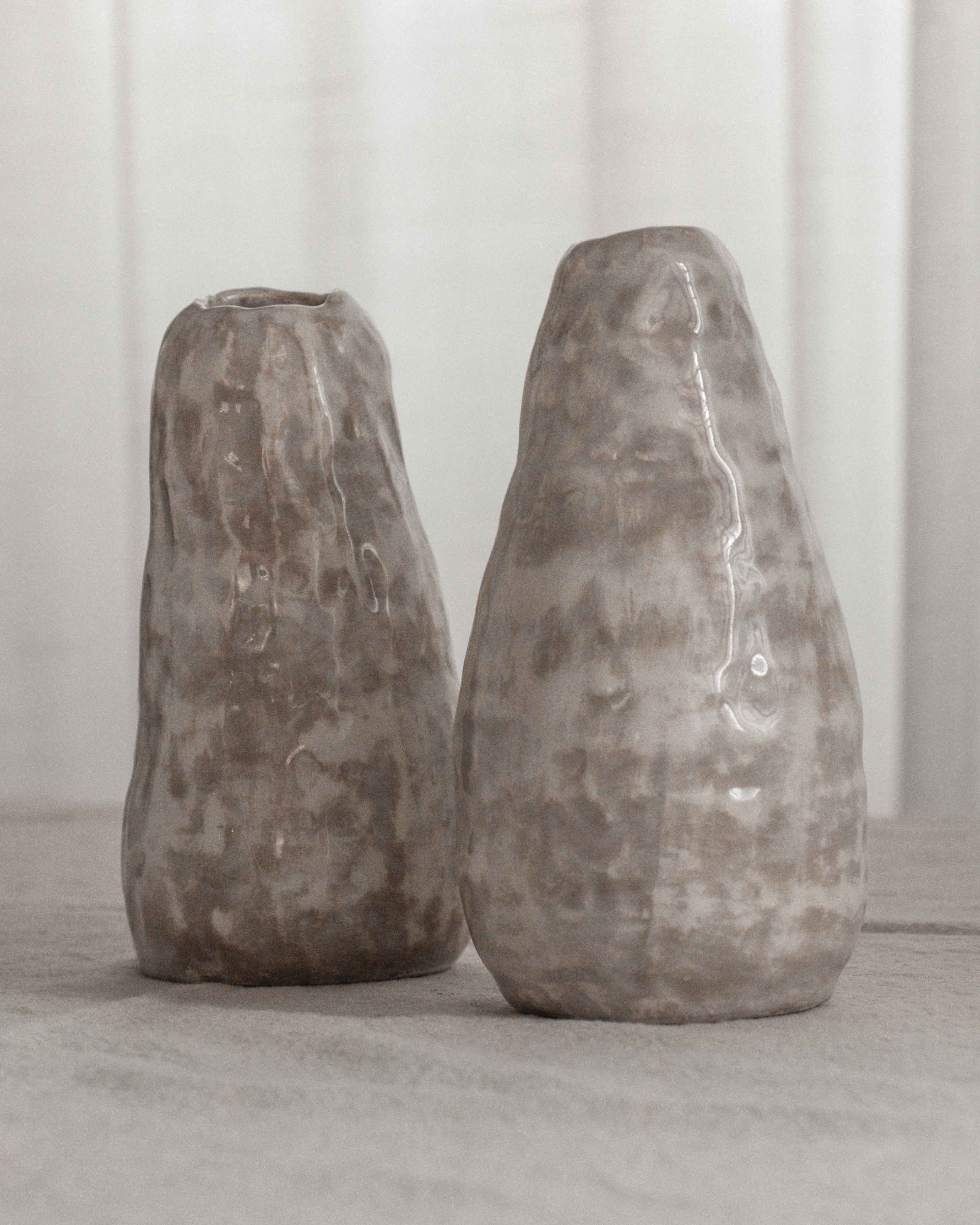 Two textured ceramic vases on a light surface with a neutral background
