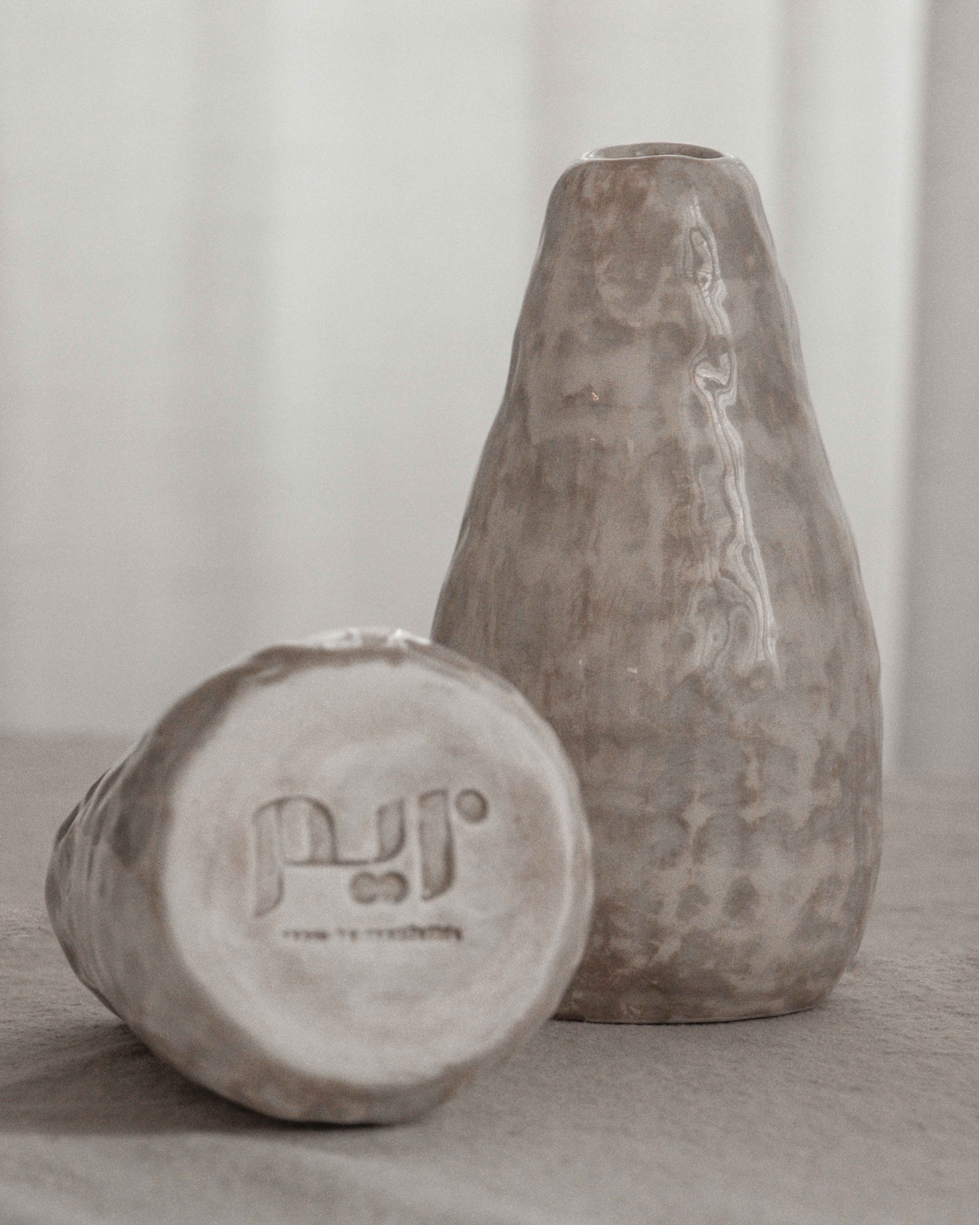 Two stone-like vases with a brand logo on a neutral background