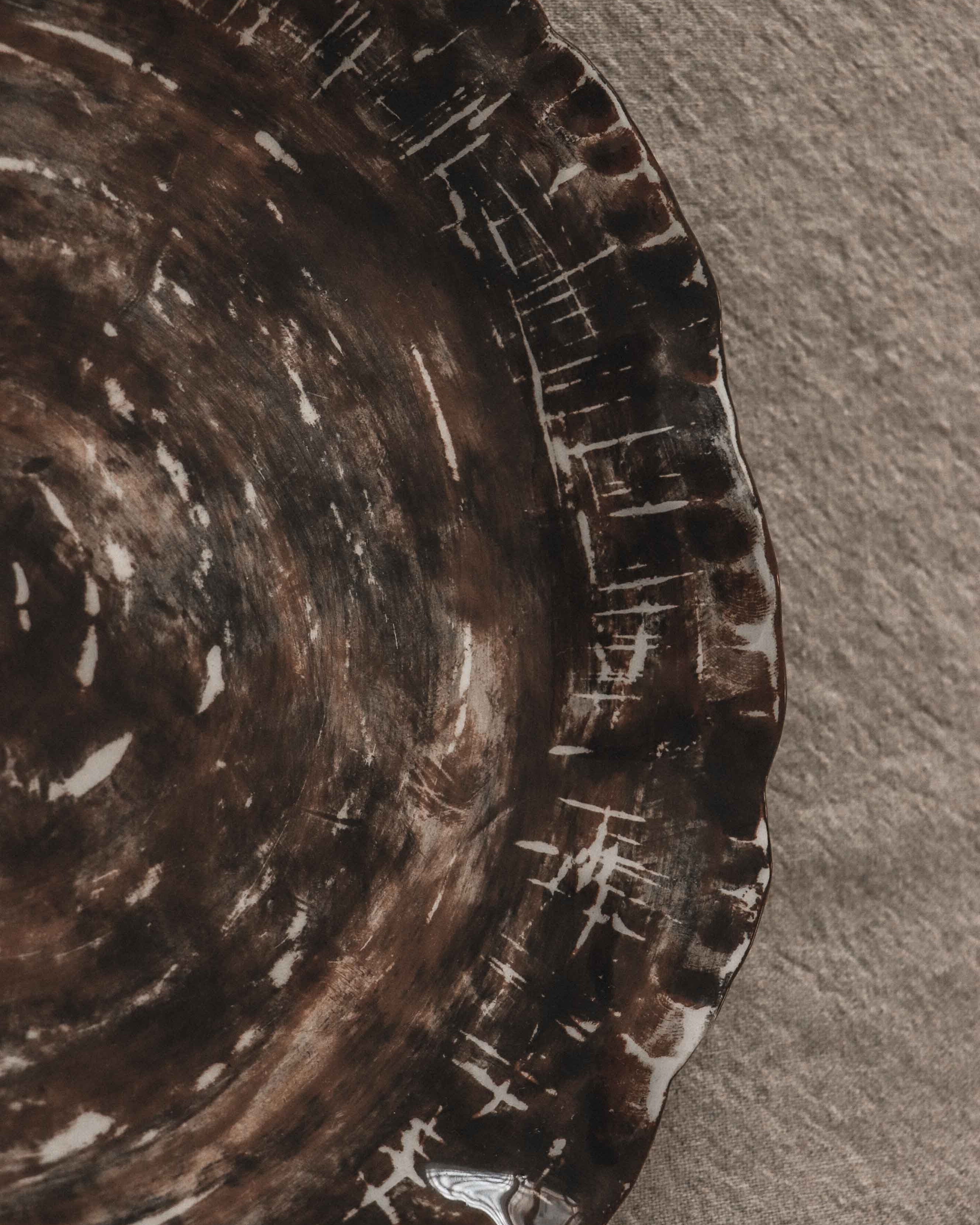 Close-up of a textured brown ceramic plate with a detailed rim.