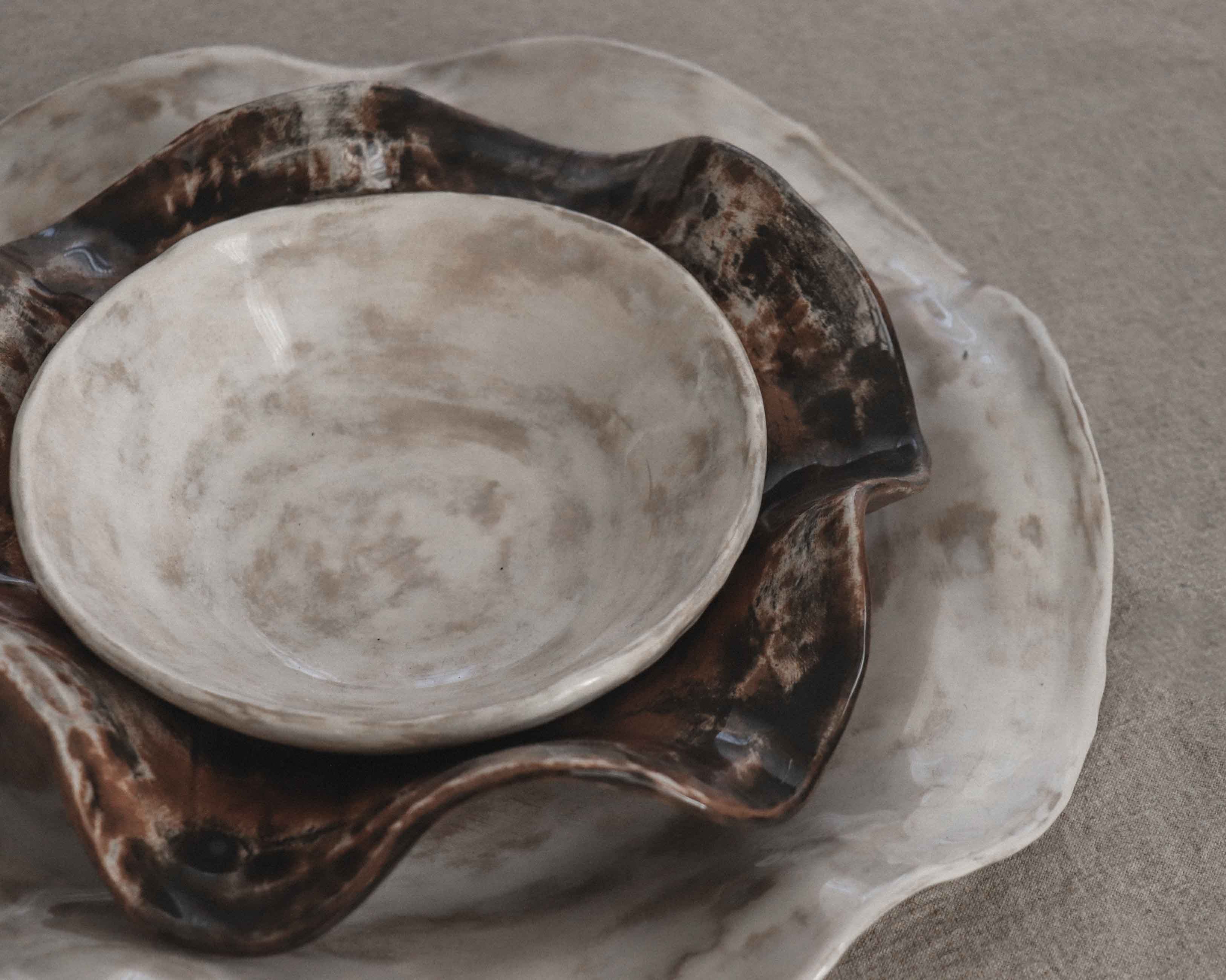 Ceramic bowl and plate with brown and white glaze on a gray background